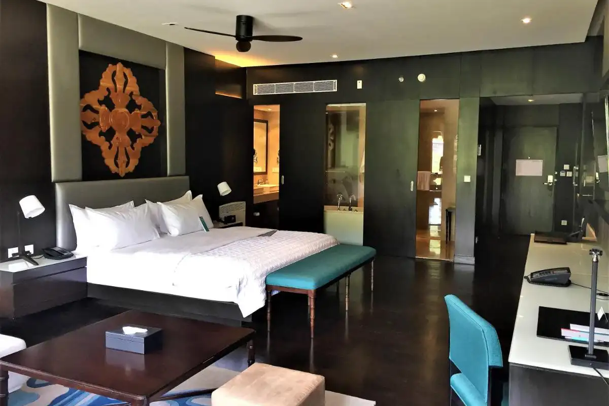 Modern hotel room in Bhutan with king bed and elegant dark interiors, a comfortable option of a Bhutan accommodation guide.