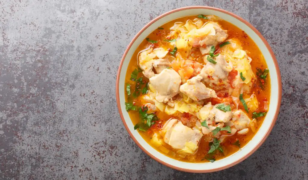 A top-down view of a bowl of Jasha Maroo, a spicy ginger-based chicken stew, showcasing authentic Bhutanese food.