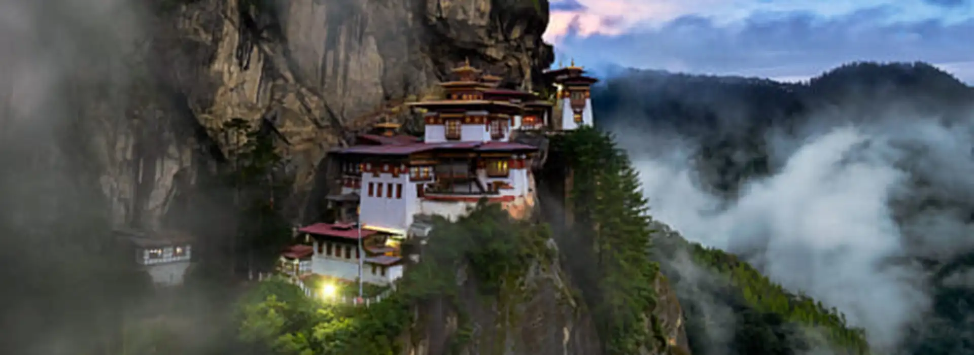 The legendary Tiger's Nest Monastery (Paro Taktsang) clinging to a sheer cliff face amidst swirling mountain mists.