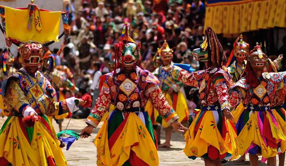 Masked dancers performing at Paro Tsechu festival, celebrating Bhutan's Culture and Traditions before a vibrant crowd in traditional attire.