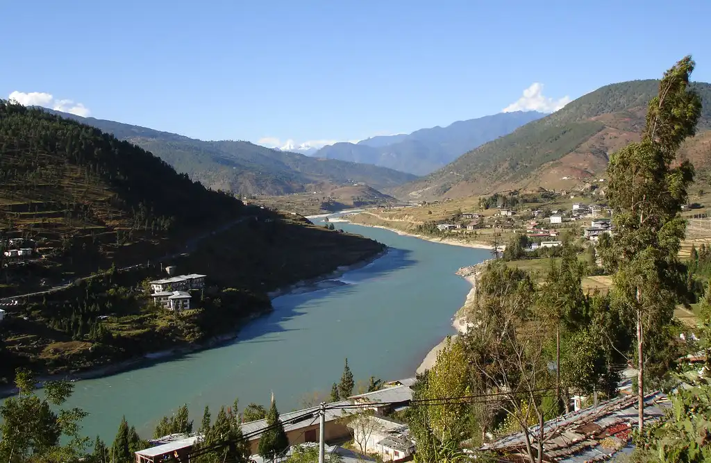 The winding Nakay Chhu river snaking through the wide, marshy floor of Phobjikha Valley, a tranquil stop on a Bhutan photography tour.