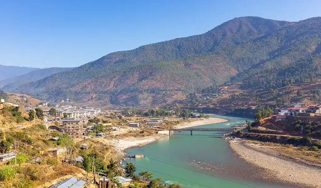 River flowing through a small village valley in Bhutan surrounded by green hills, showcasing scenic solo travel in Bhutan.