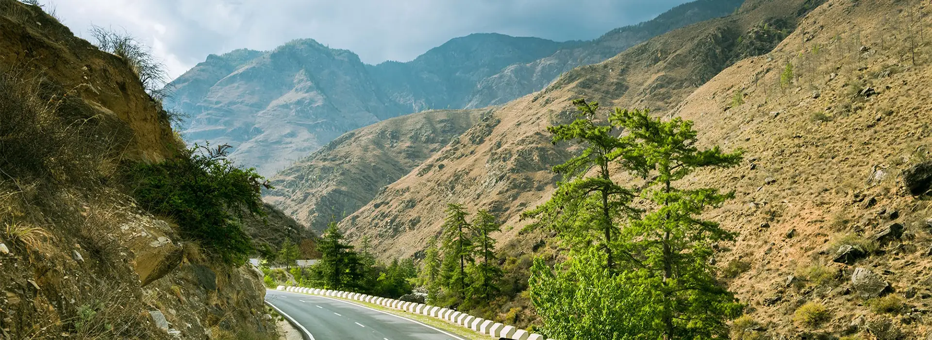 Mountain highway passing through rugged Himalayan landscape during a Bhutan road trip showcasing scenic driving routes.