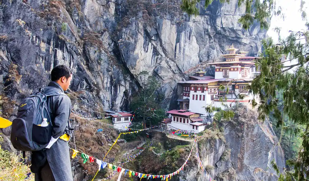 A happy traveler taking in the majestic view of the cliffside Tiger’s Nest Monastery during solo travel in Bhutan.