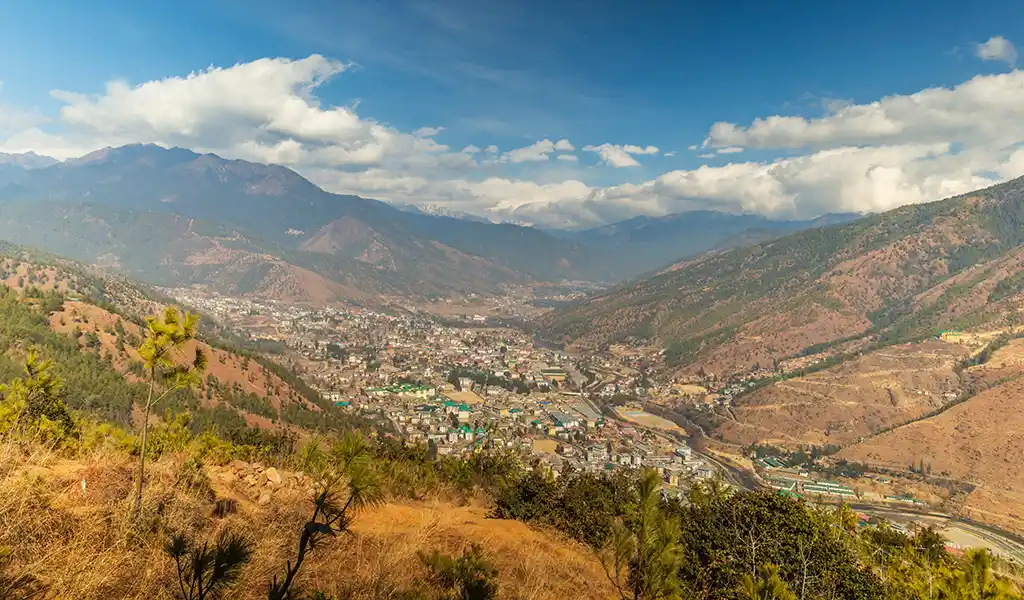 A vibrant green valley with a roaring waterfall during the summer monsoon, a unique perspective on the best time to visit Bhutan for nature lovers.