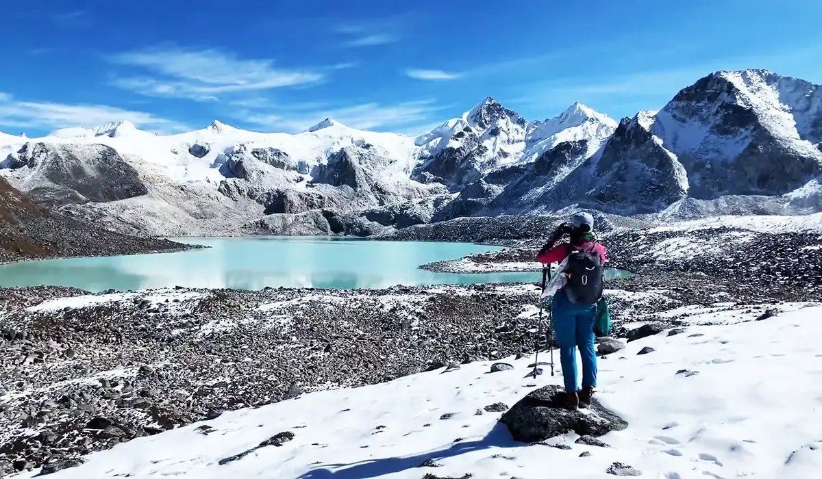Trekker overlooking turquoise glacial lake, showcasing Eco-Friendly Travel in Bhutan and pristine Himalayan nature