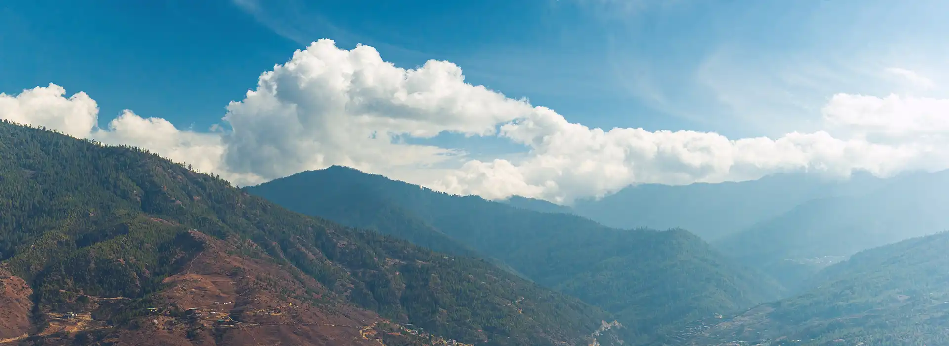 A wide panoramic view of a pristine valley in the Himalayas, highlighting the premium Bhutan travel cost and the country’s high-value tourism model in 2026.