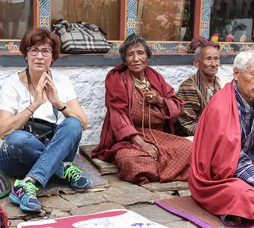 Traveler sitting with local elders in traditional dress during a cultural moment featured in a Punakha travel guide.