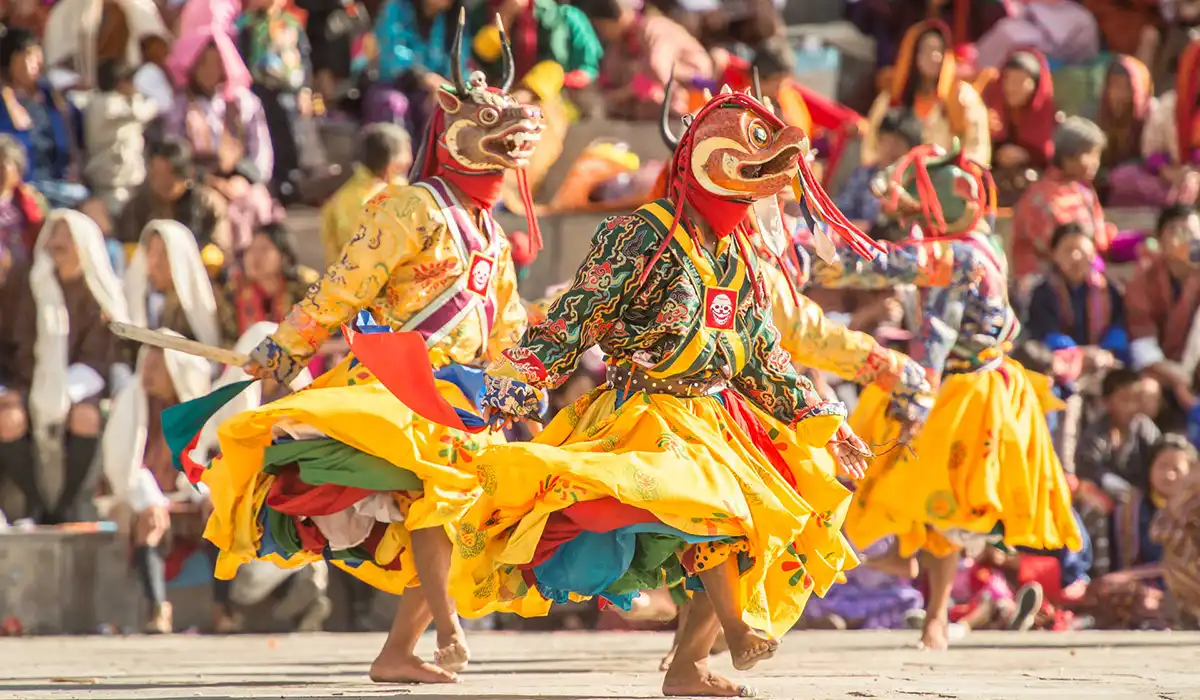 Traditional masked dancers performing at a Bhutan festival, highlighted in Bhutan travel FAQs.