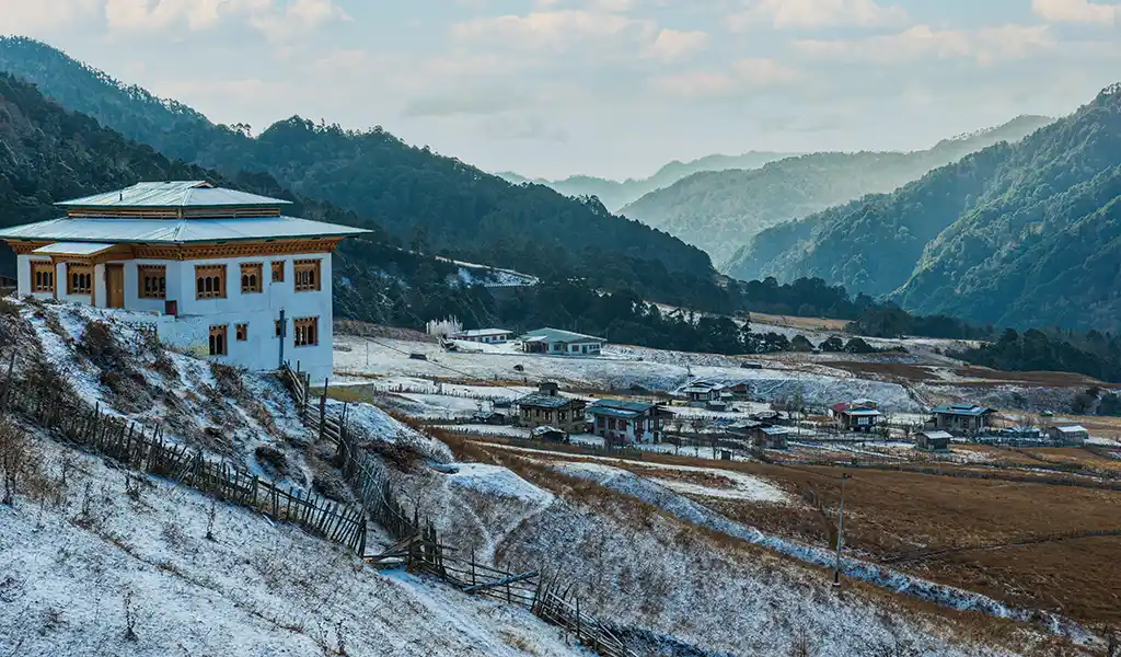 A peaceful view of a snow-covered dzong in winter, showcasing the best time to visit Bhutan for solitude and clear mountain views.