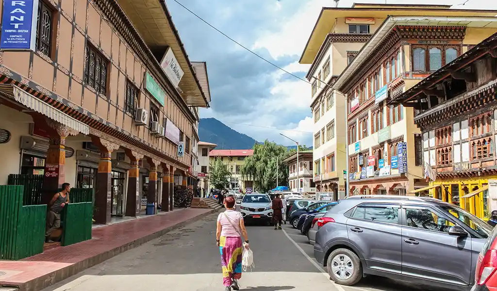 A solo woman traveler with a backpack strolling through a peaceful street in Thimphu, Bhutan Budget Travel.