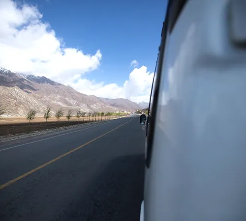 A smooth highway stretches through wide valleys and dry mountains on a Road Trip from Lhasa to Shigatse, with clear skies and open Tibetan landscapes.