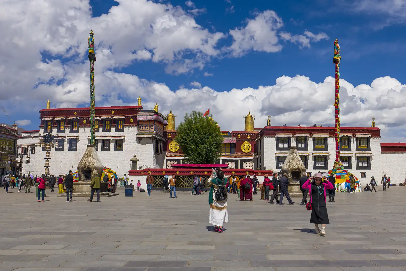 Visitors stand in the Jokhang Temple square in Lhasa, showing one of the key city landmarks travelers often visit when planning how to get to Tibet.