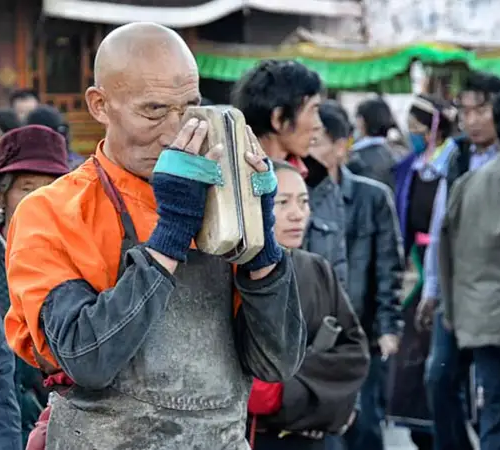 Tibetan monk praying with scripture during a traditional ritual in Lhasa, highlighting the spiritual culture visitors experience in Tibet.