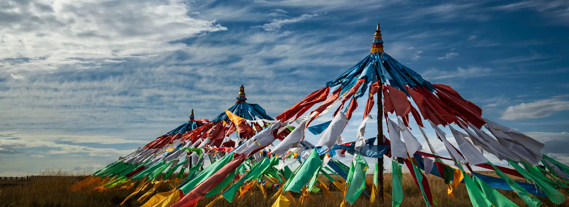 Vibrant prayer flags drape from tall wooden poles against a bright blue sky, a common sight during a traditional Tibet festival celebration.