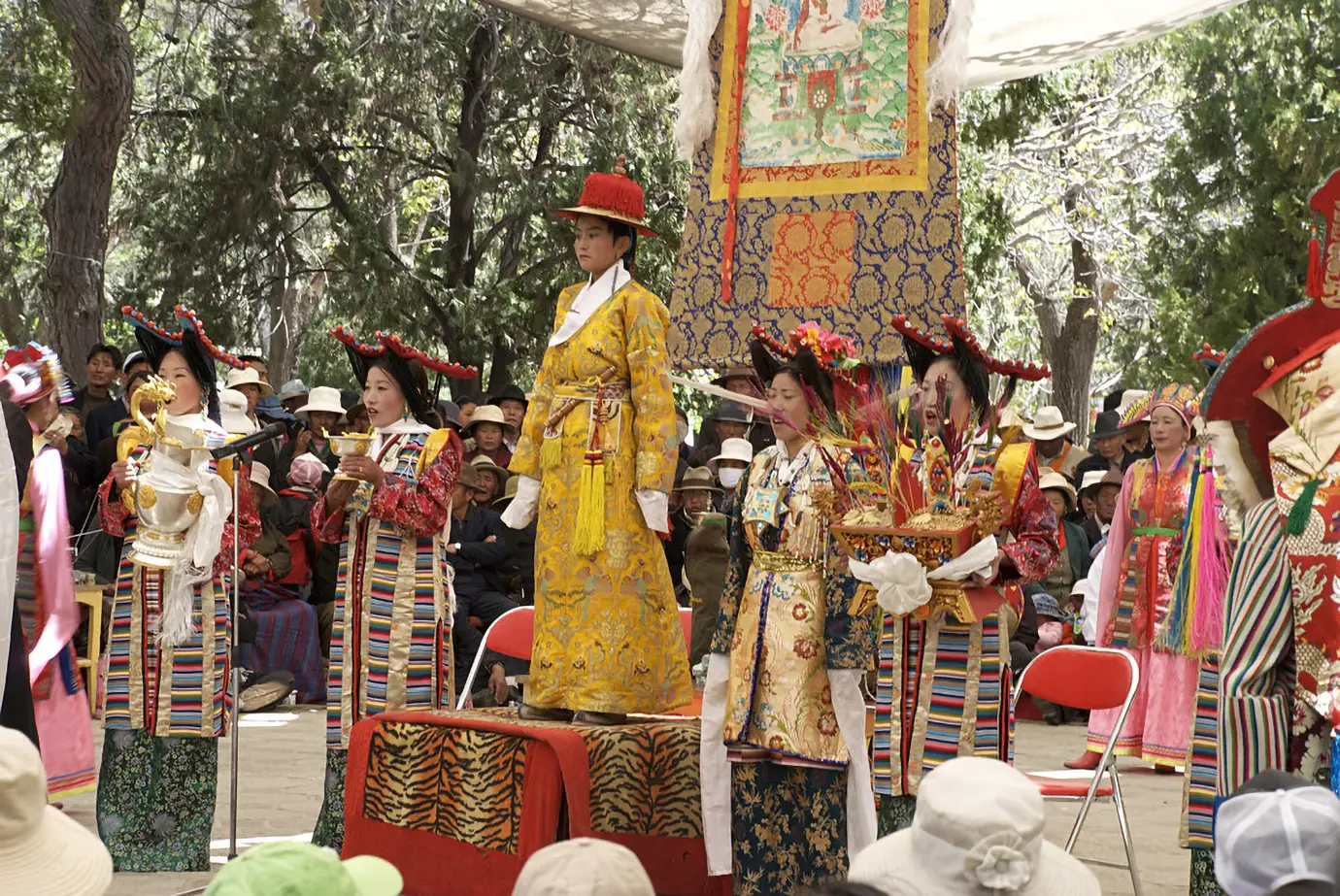 Traditional Tibetan festival ceremony with performers in colorful costumes and ceremonial robes during a Tibet spiritual tour, surrounded by local spectators and cultural ritual decorations.