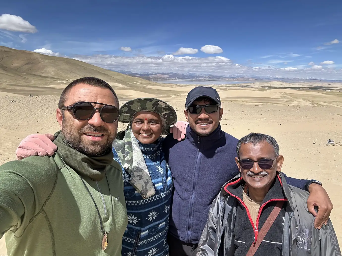 Travelers pose together in a wide mountain landscape during a Tibet Private Tour vs Group Tour experience, showing the shared social side of group travel.