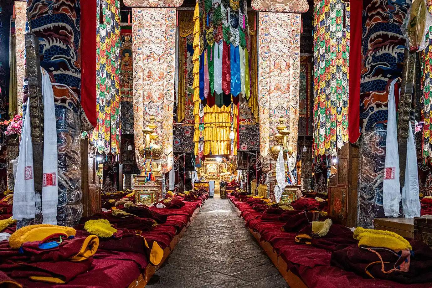 Vibrant silk banners and maroon cushions line the assembly hall of Drepung Monastery, a key cultural stop on a Tibet Tour Itinerary for First-Time Visitors.