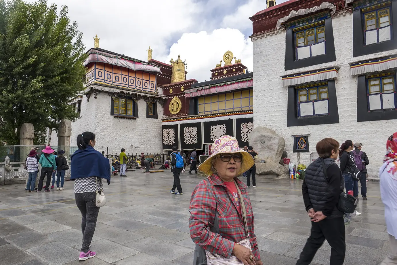 A traveler stands near Jokhang Temple in Lhasa as visitors move through the courtyard during a cultural stop on a solo Tibet travel route.