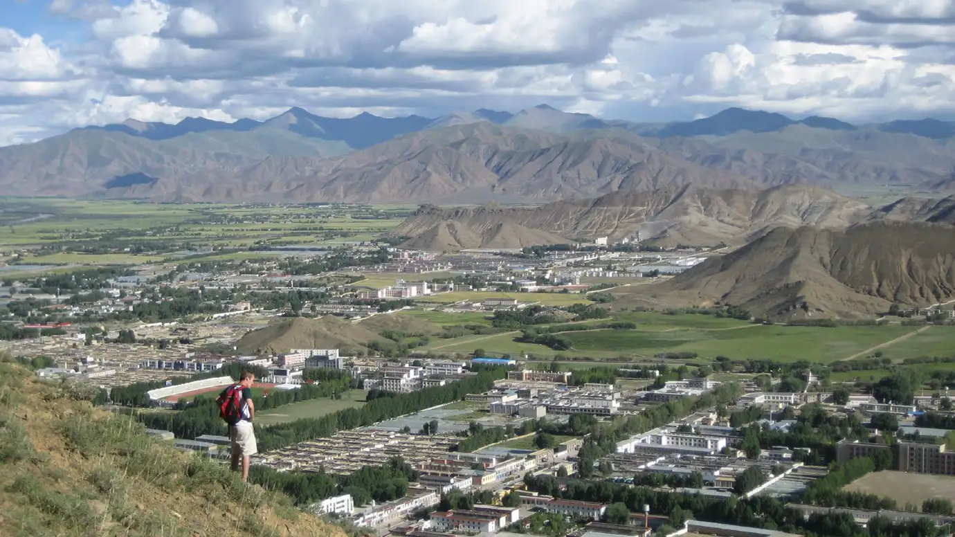 Traveler overlooking Lhasa Valley from a hillside while planning a Tibet tour itinerary