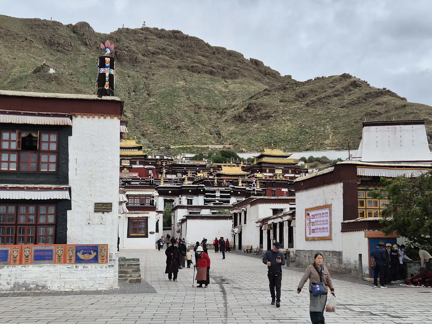Visitors walk along a paved path through the Tashilhunpo Monastery complex in Shigatse, a significant spiritual site on a Tibet Buddhist Pilgrimage Tour.