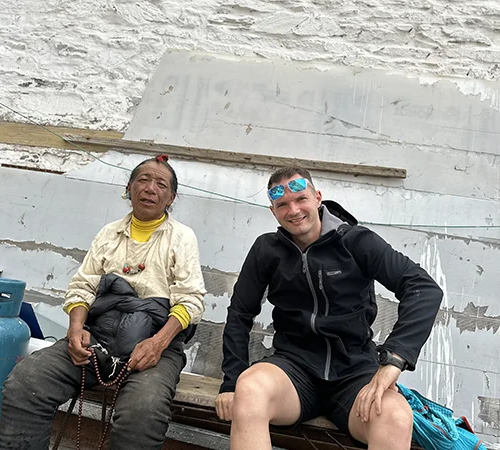 Traveler sitting with a local resident during a Tibet Private Tour vs Group Tour experience, showing a more personal and flexible cultural visit in Tibet.