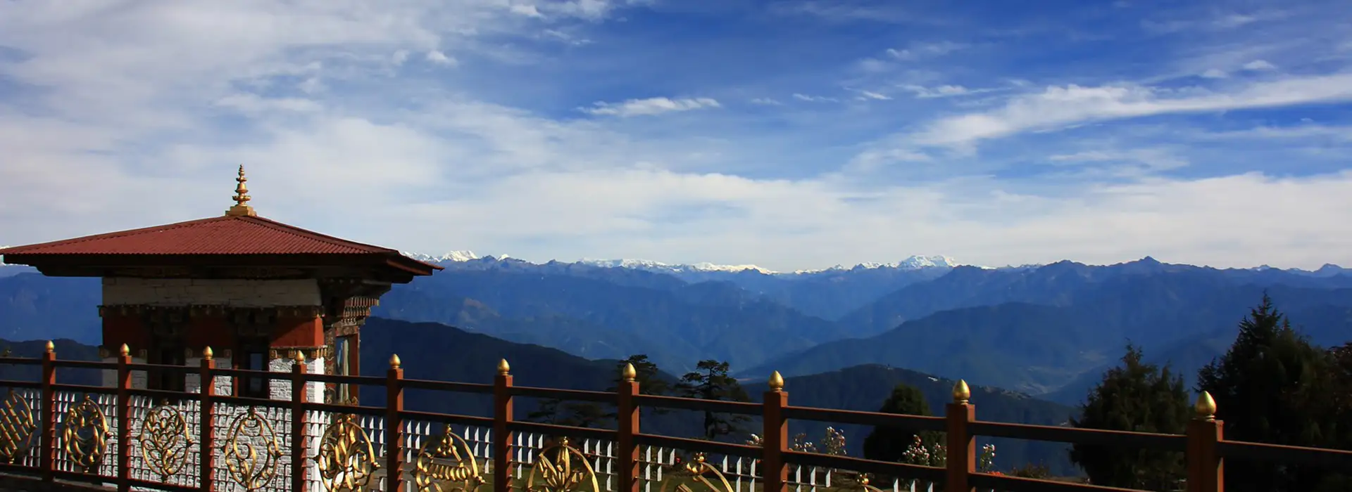 Mountain panorama from Dochula Pass in Bhutan with Himalayan peaks and traditional pavilion, highlighting high-altitude conditions travelers prepare for using a Bhutan Travel Packing List.