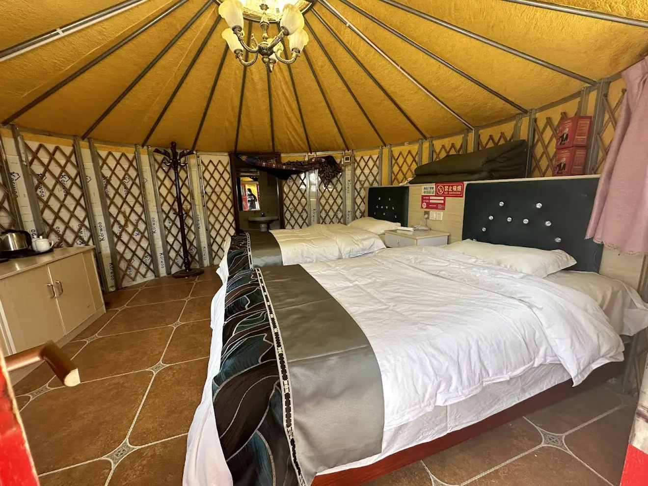 A luxury yurt interior features two large beds and traditional lattice walls. This unique lodging is a comfortable part of a Tibet tour from the USA.