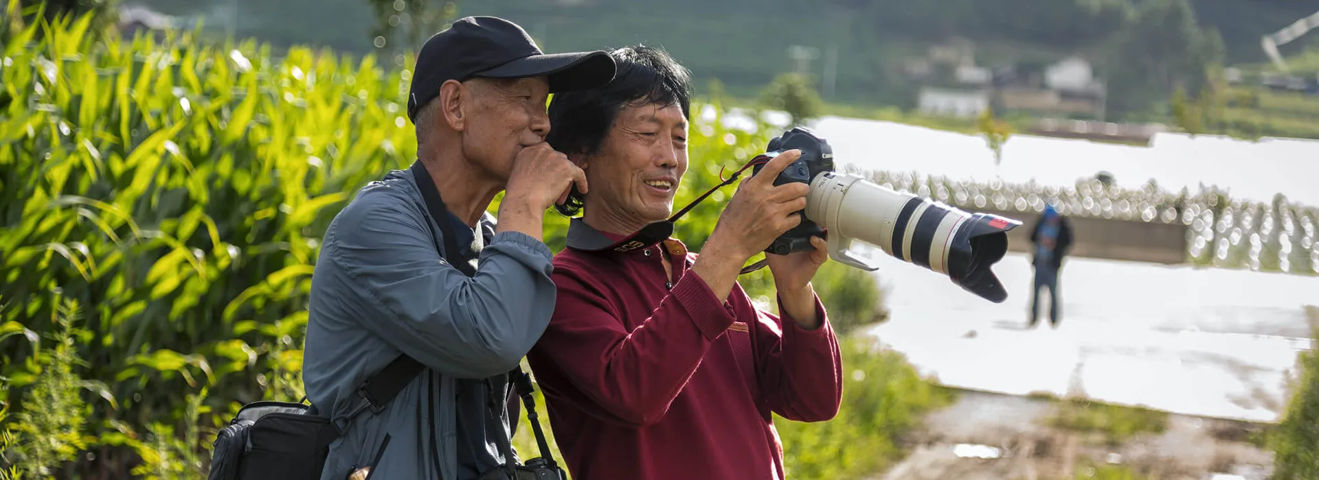 Two smiling birders review a photograph on a digital camera with a telephoto lens while participating in a professional Bhutan bird watching tour.