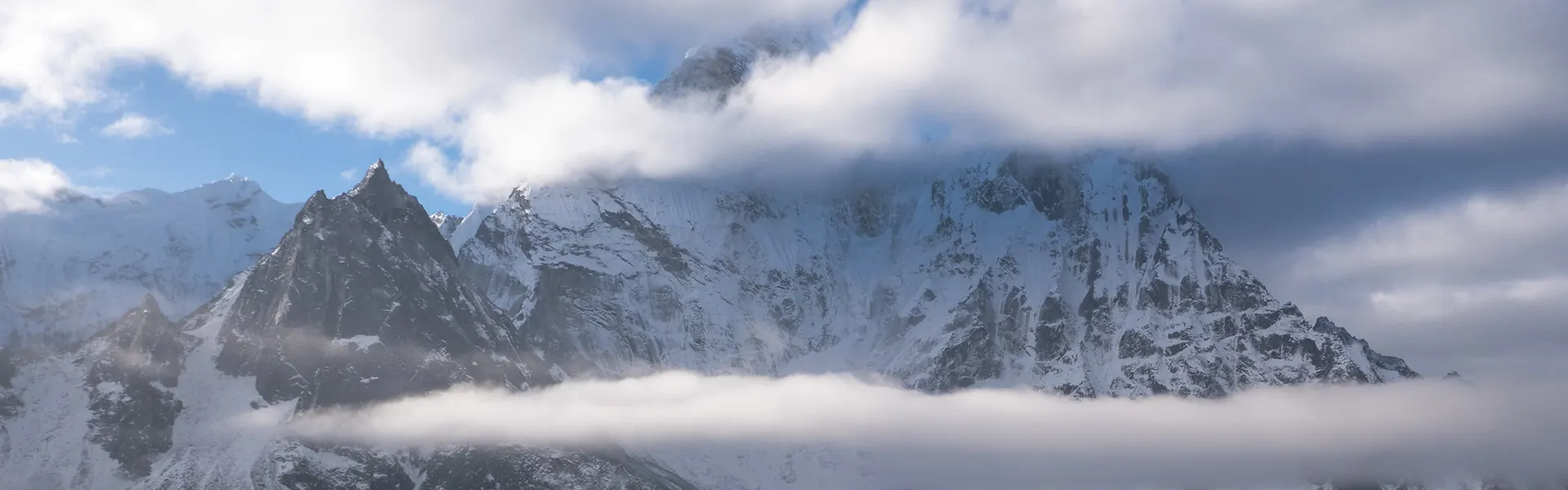 A panoramic view of jagged, snow-capped Himalayan peaks rising above a thick layer of white clouds, illustrating the terrain described in this Gokyo Lakes Trek Guide.