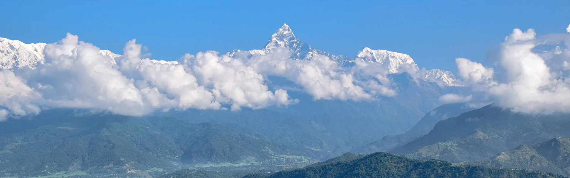 A breathtaking panoramic photograph showing the snow-capped Himalayan peaks rising dramatically above a thick sea of white clouds, illustrating the majestic views from a Pokhara Travel Guide.