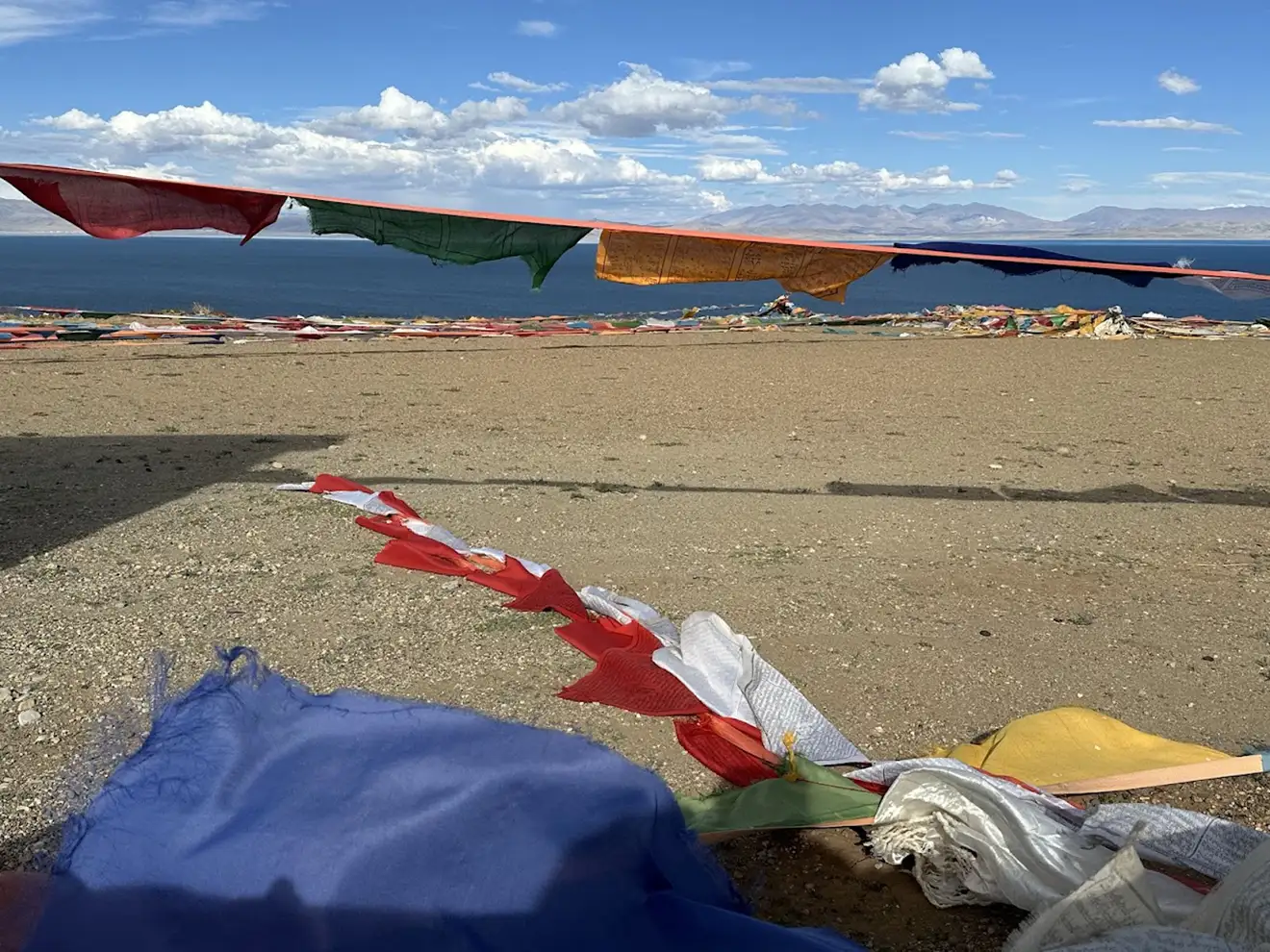 Colorful Buddhist prayer flags flutter in the wind along the shores of Lake Mansarovar. Travelers must secure a Tibet Military Permit to visit this sacred high-altitude region.