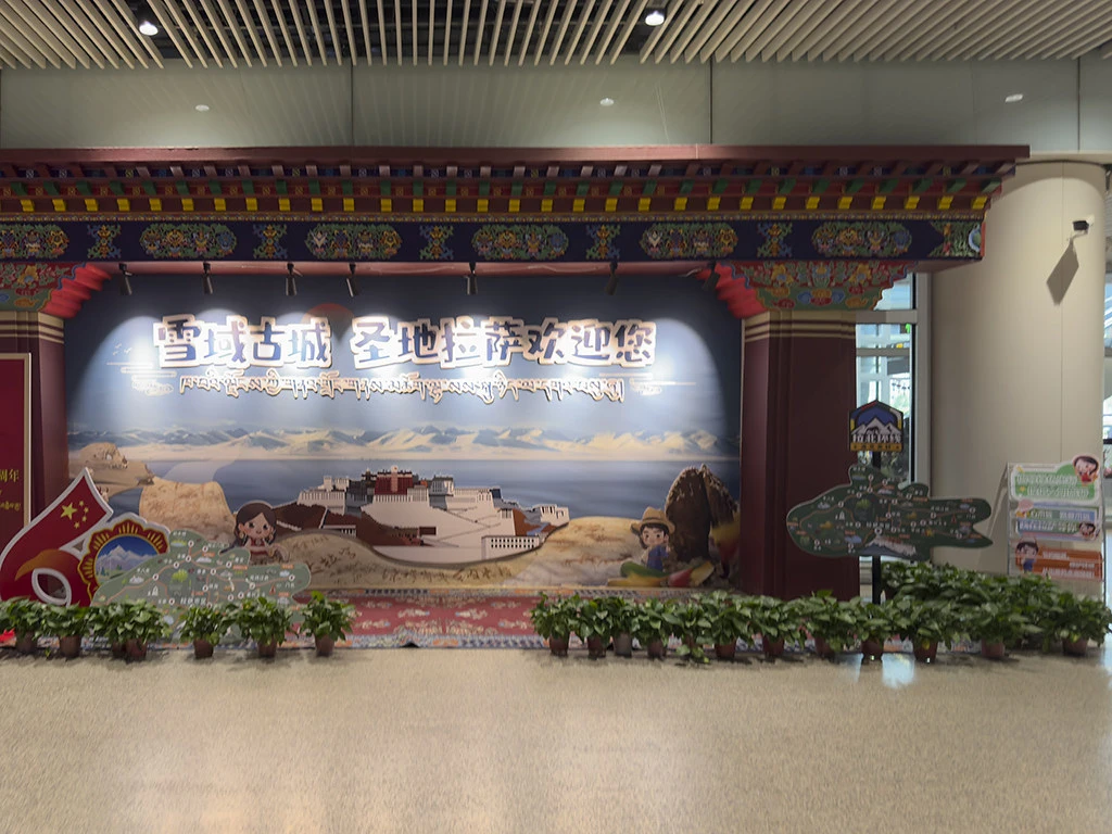 A colorful welcome mural at Lhasa Gonggar Airport features the Potala Palace and local landscapes, greeting travelers arriving for their Lhasa to Everest Base Camp and Namtso Lake Tour.