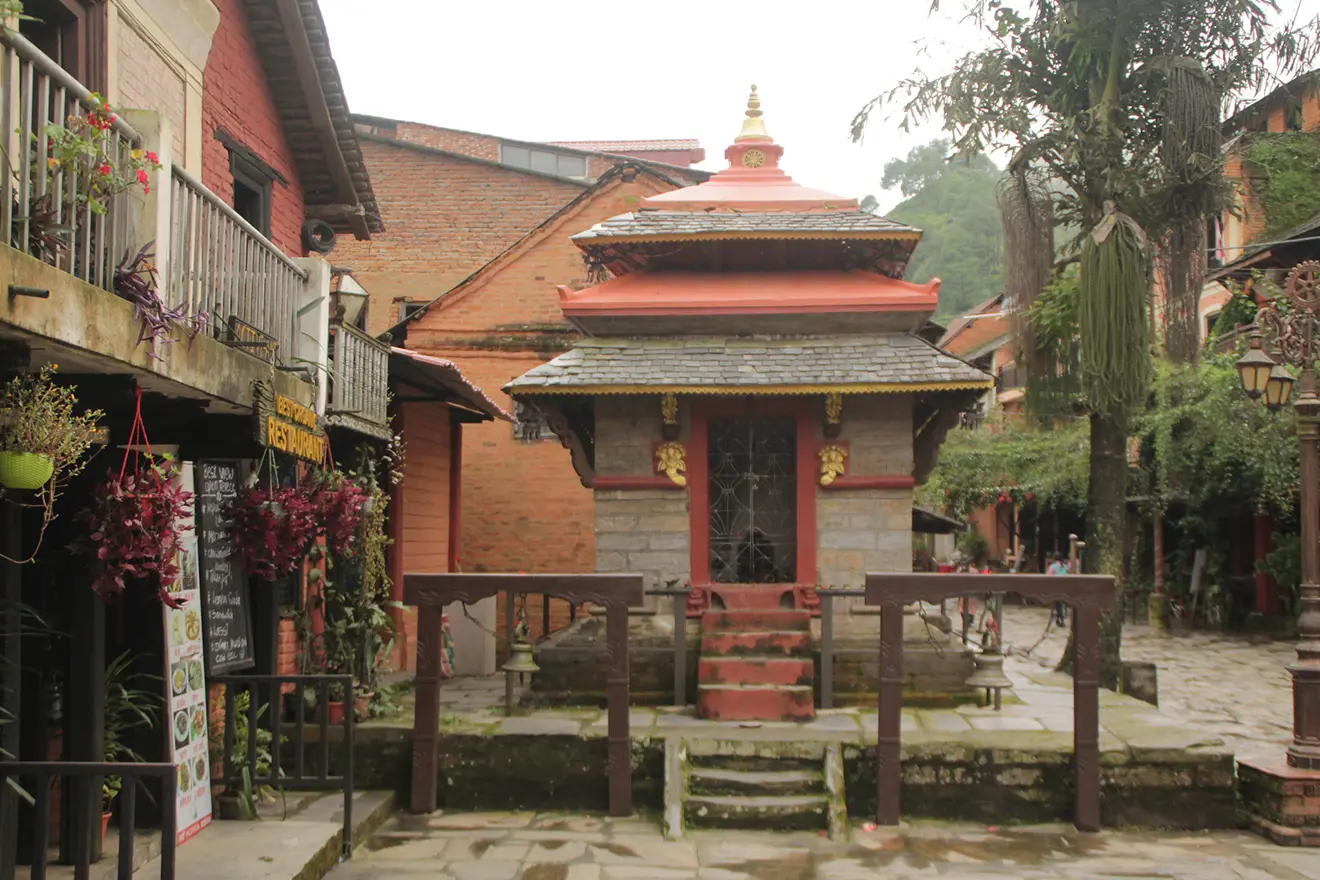 A traditional stone temple with a tiered roof stands in a quiet courtyard in Bandipur, making it a highlight for the best short trips in Nepal.