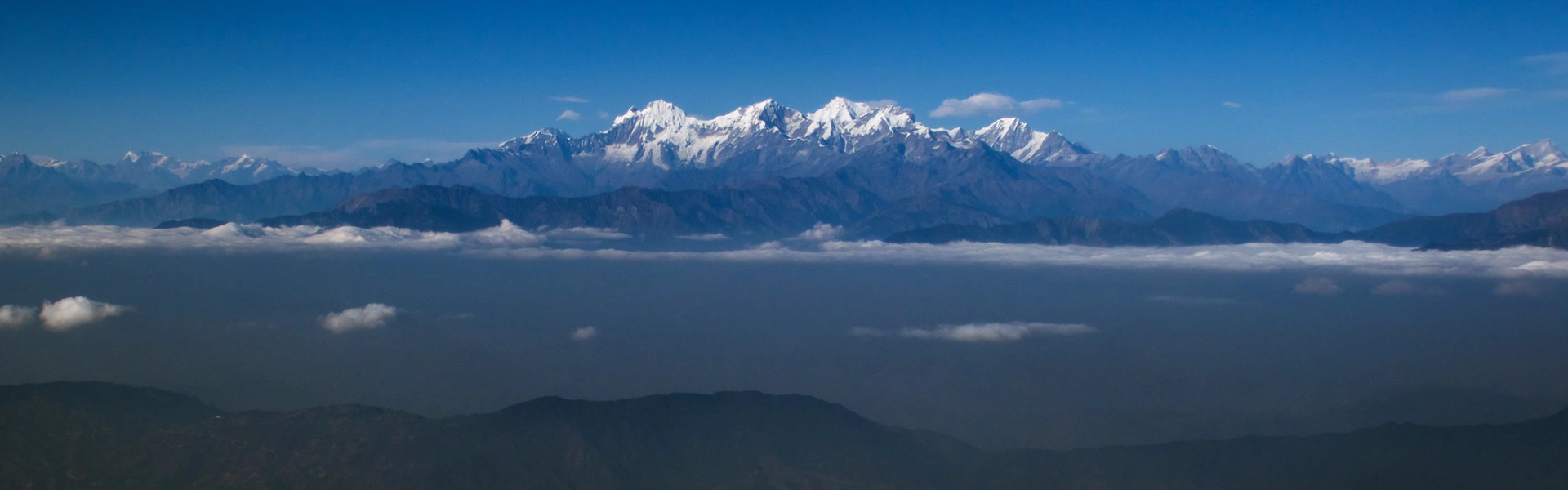 A panoramic view of jagged, snow-capped Himalayan peaks rising above a thick layer of white clouds, illustrating the destination of this Gokyo Lakes Trek Guide.