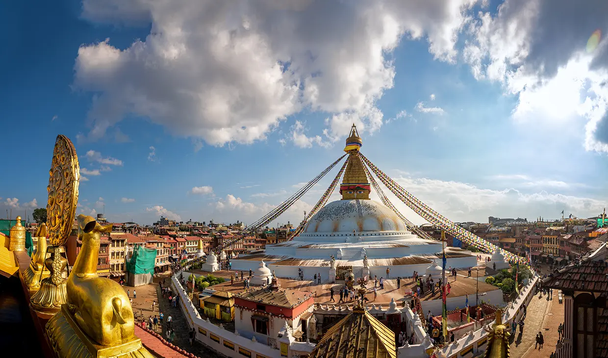 A scenic view looking down from a cafe balcony shows people milling around the base of the massive Boudhanath Stupa, among the essential things to do in Kathmandu.