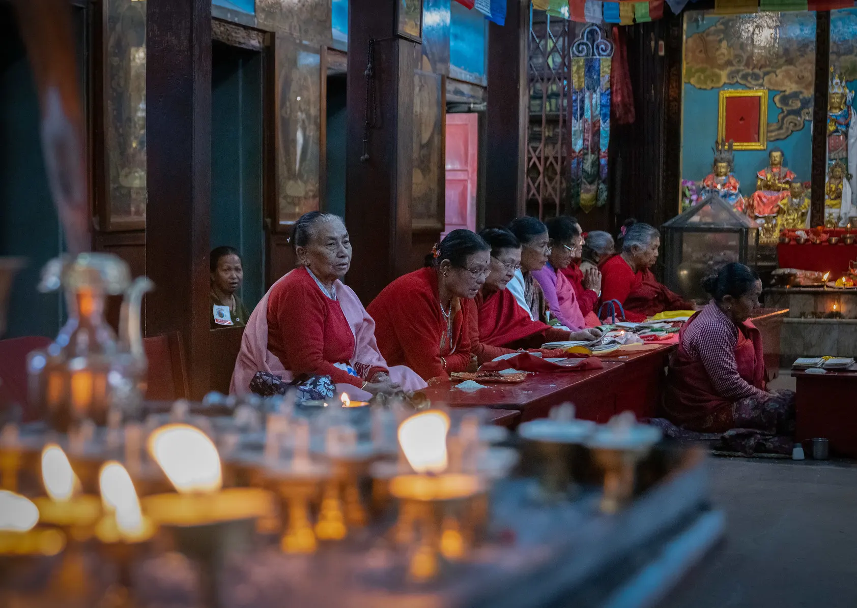 Nepali women in traditional attire gather and pray at a long wooden table during a cultural ceremony, showcasing the best cultural destinations in Nepal.