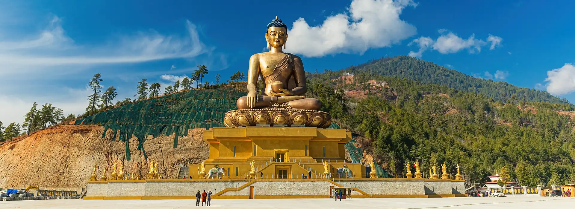 A giant golden Buddha Dordenma statue sits on a hillside overlooking Thimphu valley, a major landmark visited during a Bhutan Golden Triangle Tour.