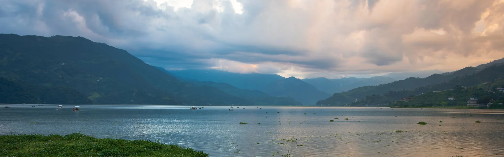 A wide panoramic sunset view over Phewa Lake with small boats and distant mountains, highlighting one of the best places to visit in Pokhara.