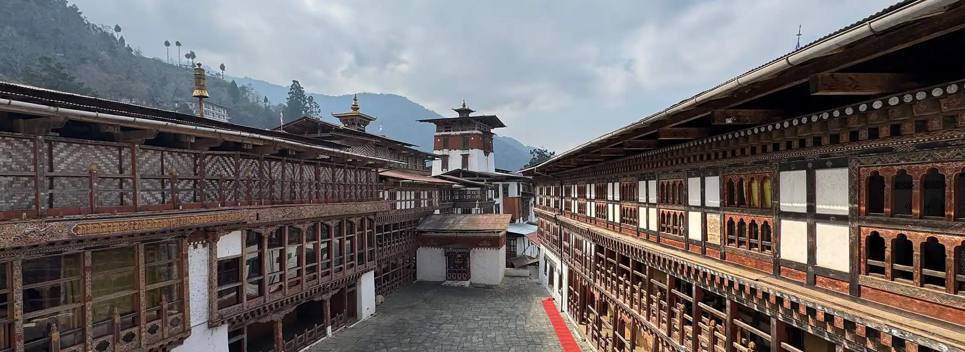 The inner courtyard of a traditional stone and wood fortress features intricate carvings and tiered roofs, a highlight of any Classic Bhutan Tour.
