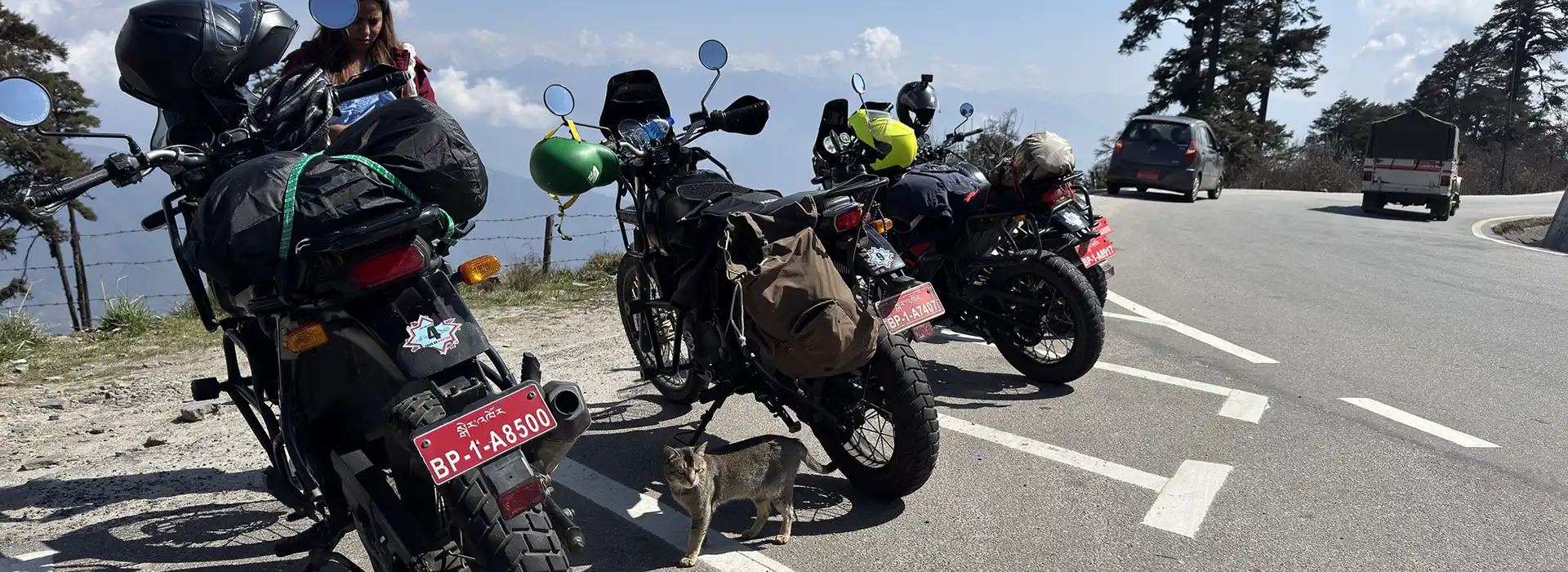 Several adventure motorcycles with luggage sit parked along a scenic mountain road during a professional Bhutan motorcycle tour in the high Himalayas.