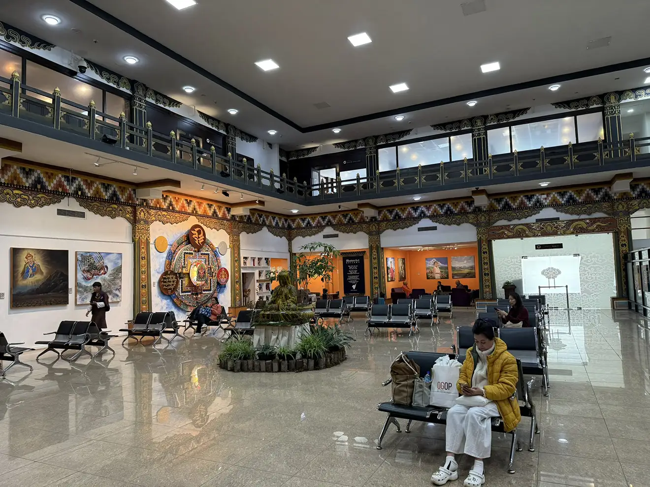 Travelers wait in the Paro International Airport terminal, which features traditional Bhutanese art and decor, serving as the gateway for the Druk Path Trek.