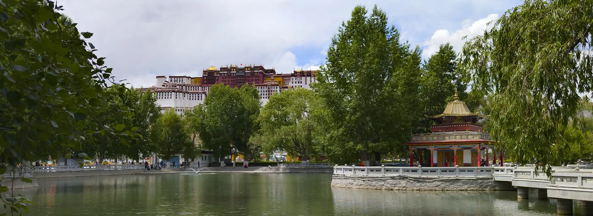 The historic Potala Palace stands on a hill above a peaceful park lake with a golden pavilion, an iconic start to the Lhasa to Everest Base Camp and Namtso Lake Tour.