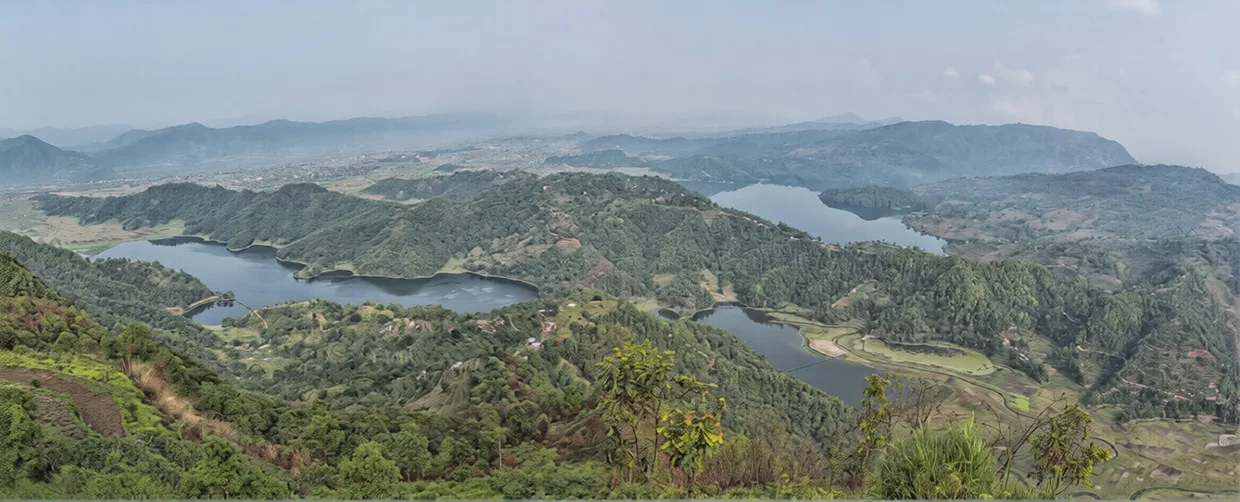 A wide-angle panoramic view of Begnas and Rupa Lakes nestled between lush green hills, highlighting the serene natural beauty found in a Pokhara Travel Guide.