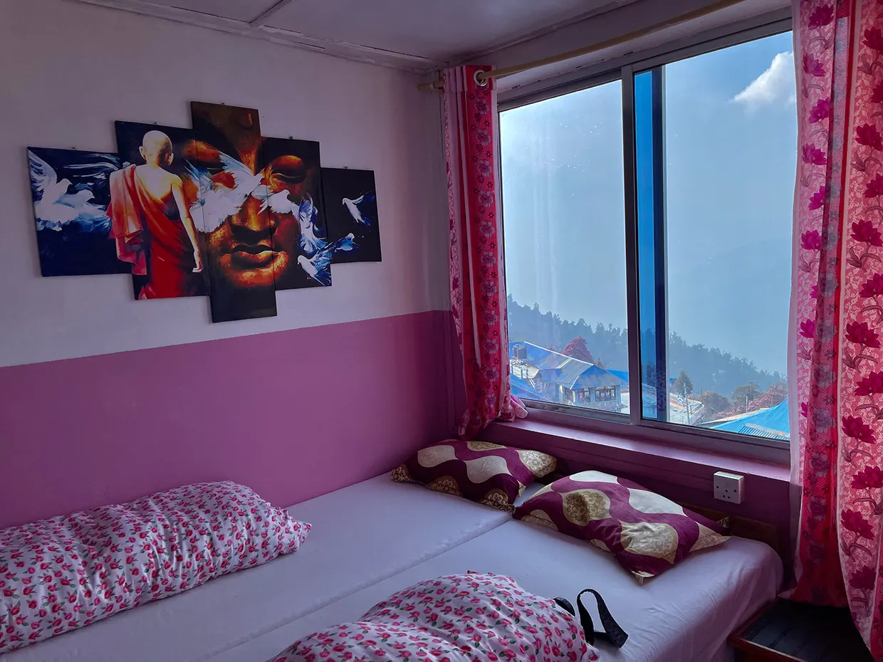 A cozy, tidy mountain teahouse room features warm wooden walls, comfortable twin beds, and panoramic mountain views. This simple stay is a key comfort in our Beginner's Guide to Hiking.