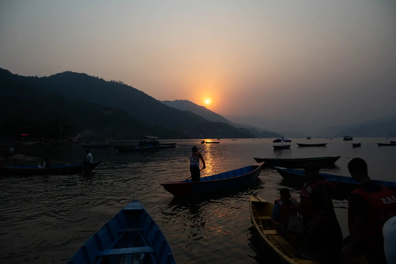Traditional wooden boats rest on the calm waters of Phewa Lake at sunset, showcasing the natural beauty found in the best cities to visit in Nepal.