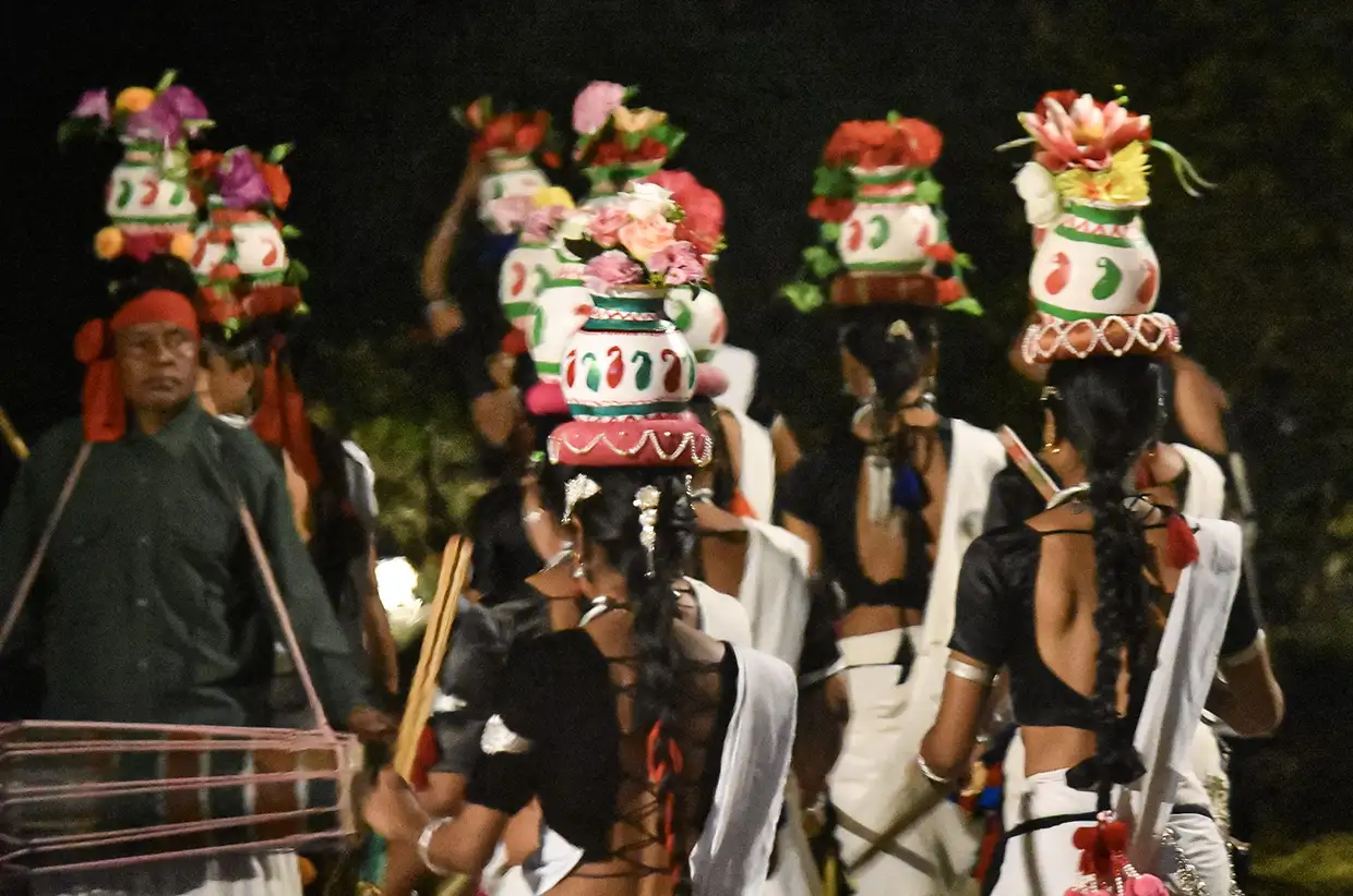 Tharu women perform a traditional stick dance while balancing colorful decorated pots on their heads, a cultural highlight featured in our Chitwan Travel Guide.