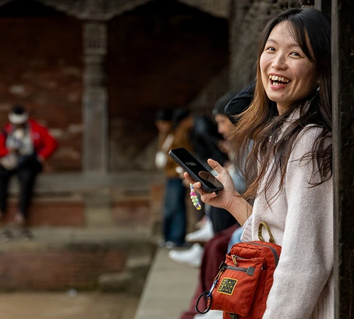 A cheerful traveler smiling while exploring ancient architecture and cultural sites in Kathmandu, one of the best cities to visit in Nepal.