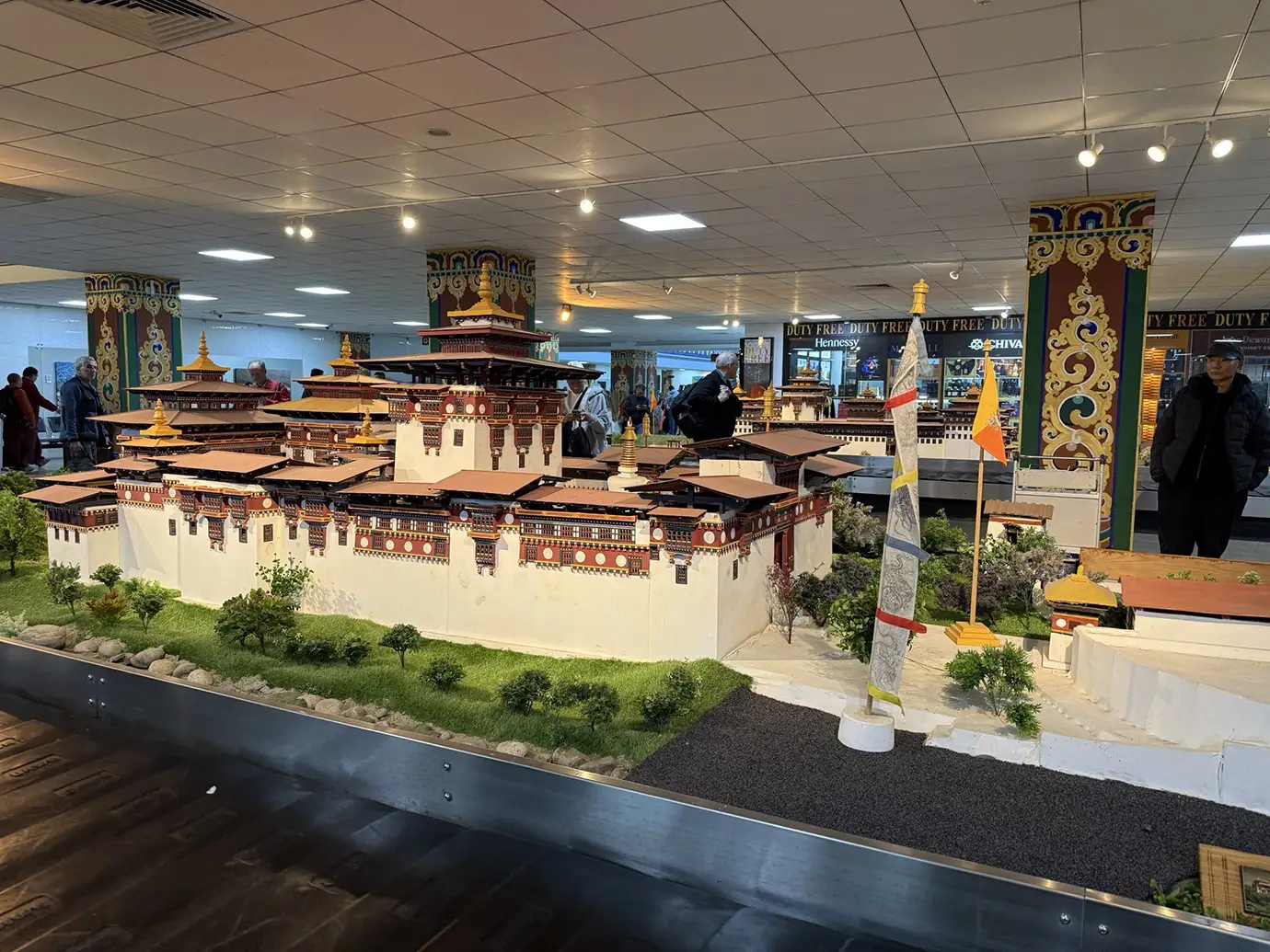 A detailed model of a Bhutanese monastery on display in an airport. This intricate replica prepares travelers for a cultural Phobjikha Valley Nature Tour.