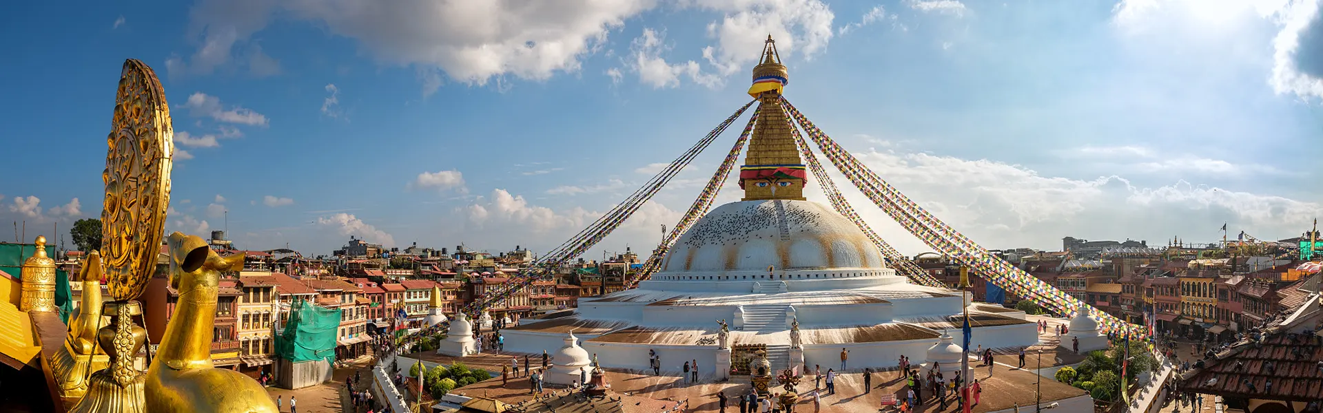 A stunning wide-angle view of the Boudhanath Stupa with colorful prayer flags and a golden spire, showcasing the best spiritual things to do in Kathmandu.